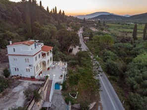 A white villa with a red-tiled roof, a paved patio, and a staircase leading to the entrance. - Amalia Country House (Zakynthos)