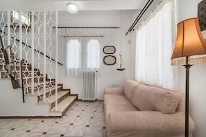 A staircase with white railings, a beige sofa, and a lamp. - Amalia Country House (Zakynthos)