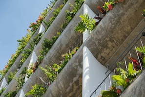 A building with multiple balconies, each with plants and flowers. - Nexus House An Thuong – Boutique Hotel Near My Khe Beach (Da Nang)