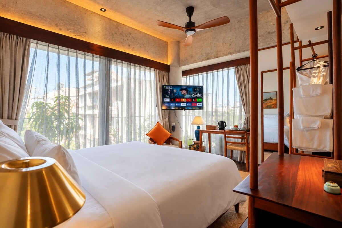 Quarto de hotel com cama, televisão, escrivaninha e uma cadeira.