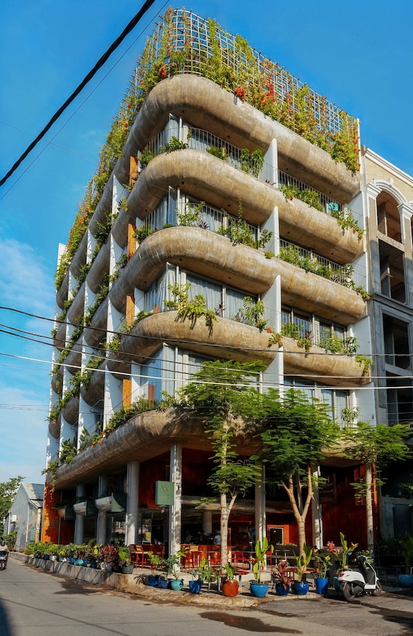 A multi-story building with balconies covered in plants. - Nexus House An Thuong – Boutique Hotel Near My Khe Beach (Da Nang)