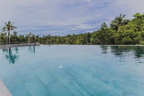 A clear blue infinity pool with a view of dense tropical foliage and palm trees. - Srithanu Riverside Pool Villa - 3BR (Tambon Ko Pha-ngan)