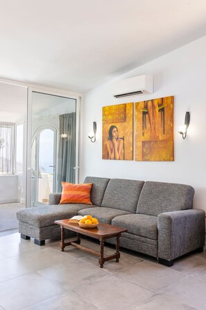 Ein modernes Wohnzimmer mit einem grauen Sofa, einem Holztisch und zwei an der Wand befestigten Kunstwerken.