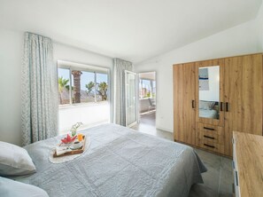 Ein Schlafzimmer mit Bett, einem Holzschrank und einem Balkon mit Blick.