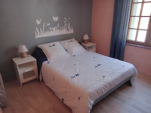 A bedroom with a bed, two bedside tables, a wall mural, and a window with curtains. - Gite La Granica (restored barn) (Bosset)