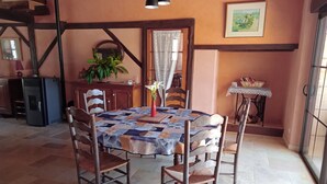 A dining area with a table covered in a quilt, surrounded by wooden chairs. - Gite La Granica (restored barn) (Bosset)