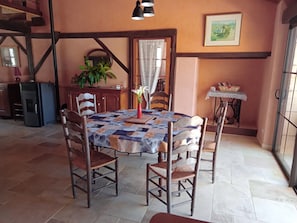 A dining area with a table covered in a quilt, surrounded by wooden chairs. - Gite La Granica (restored barn) (Bosset)