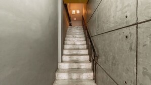 A concrete staircase with metal railings, leading to a landing with a light fixture. - Nawin Hotel Donmueang (Bangkok)
