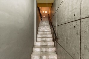 A concrete staircase with metal railings, leading to a landing with a light fixture. - Nawin Hotel Donmueang (Bangkok)
