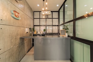 A reception desk with a modern design, a coffee sign, and a large window with a view. - Nawin Hotel Donmueang (Bangkok)