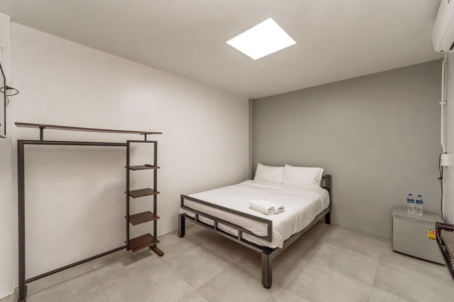 A bedroom with a bed, a wardrobe, a nightstand, and a ceiling light.