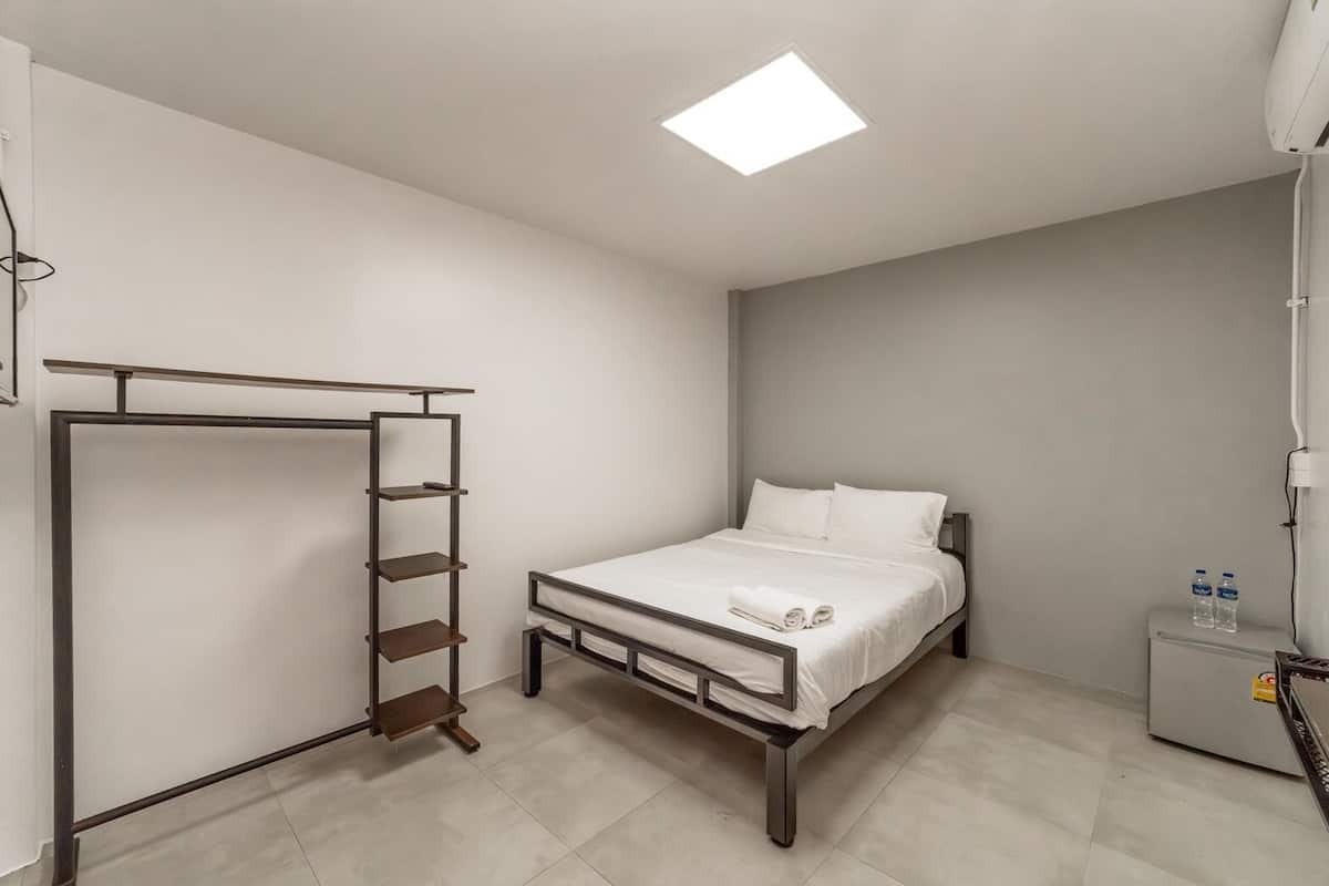 A bedroom with a bed, a wardrobe, a nightstand, and a ceiling light.