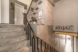A staircase with a metal railing, a brick wall, and a 'HOME' sign. - Nawin Hotel Donmueang (Bangkok)
