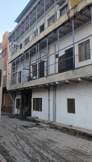 A multi-story building with a balcony, a door, and a window.