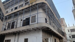 A multi-story building with a curved facade, metal mesh windows, and visible structural elements. - Shri Bankey Bihari Yatri Niwas Homestay  (Vrindavan)
