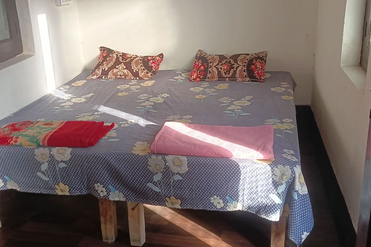 A bed with floral bedding, pillows, and a blanket.