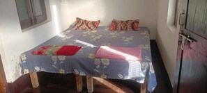 A single bed with floral bedding, a wooden headboard, and a red pillow. - Shri Bankey Bihari Yatri Niwas Homestay  (Vrindavan)