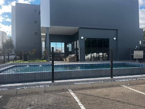 Ein modernes Gebäude mit Schwimmbad, einer überdachten Terrasse und Blick auf die Umgebung.