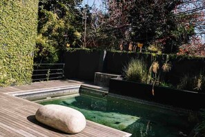 Ein Pool mit Holzterrasse und Steinelement.