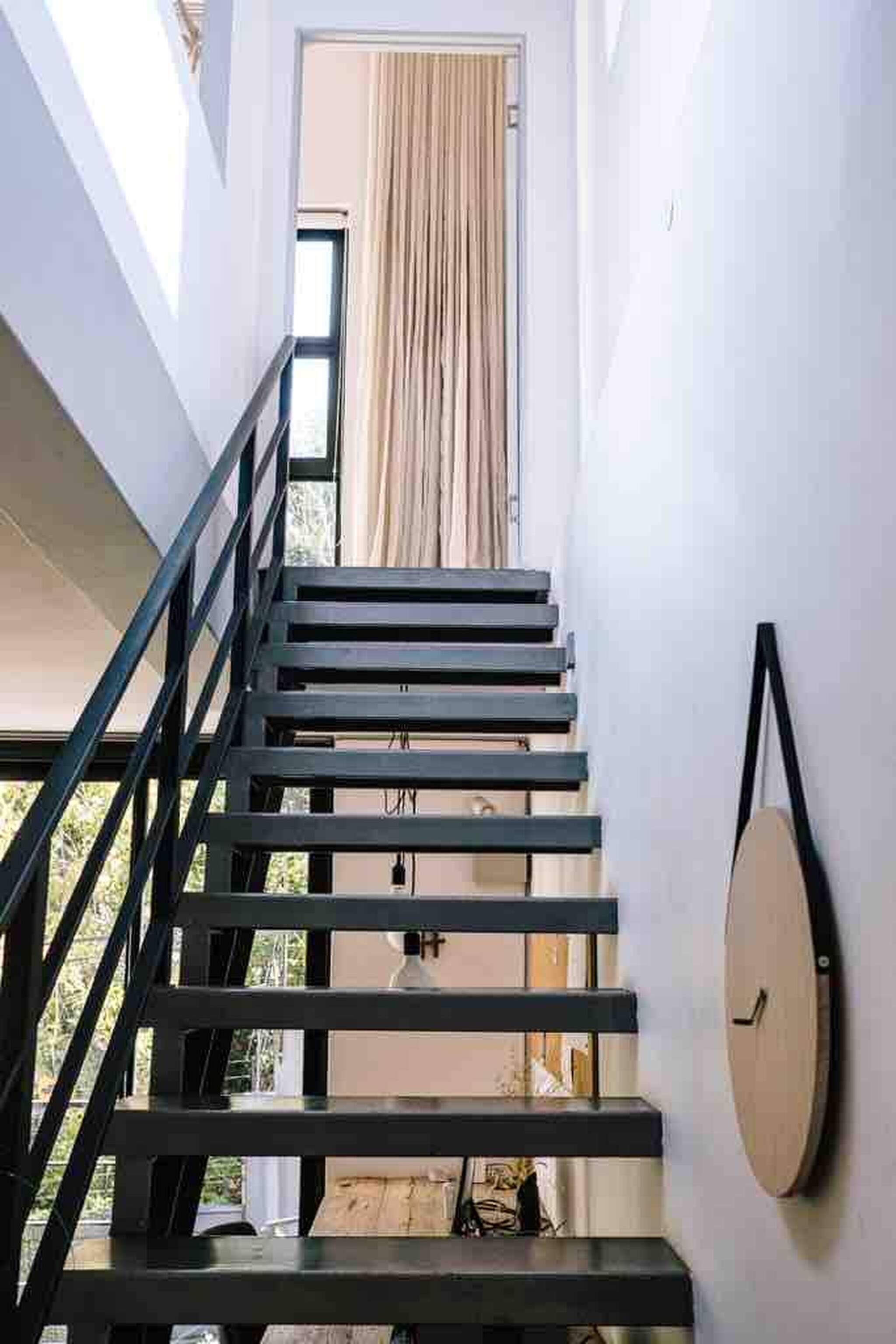 A staircase with a black railing, a wooden door at the top, and a round wall clock.