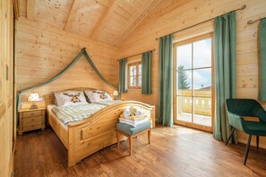 Ein Schlafzimmer einer Holzhütte mit Bett, Nachttisch, Stuhl und großem Fenster.