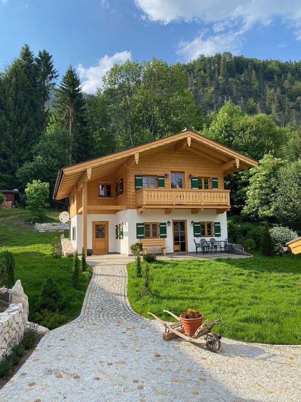 Ein zweistöckiges Holzhaus mit einem Balkon, einem Steinweg und einem Garten.