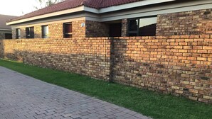 A brick building with a tiled roof, a paved walkway, and a grassy area.