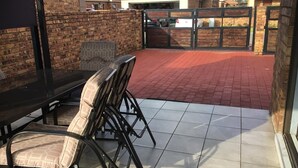 A patio area with a table and chairs, a brick wall, and a gated entrance.