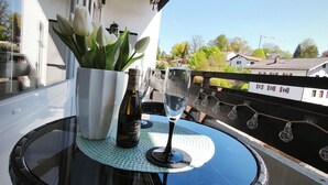 A round glass table with a bottle of wine and a glass on a balcony. - Apartment with balcony for max. 4 persons (Prien am Chiemsee)