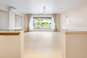 Ein geräumiges Zimmer mit großem Fenster, Deckenventilator und Blick auf einen Garten mit einer gelben Elefantenstatue.