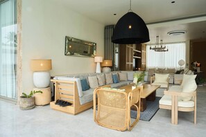 Ein modernes Wohnzimmer mit einer Couch, einem Esstisch und Stühlen. An der Wand hängt ein großer Spiegel und eine Hängelampe.
