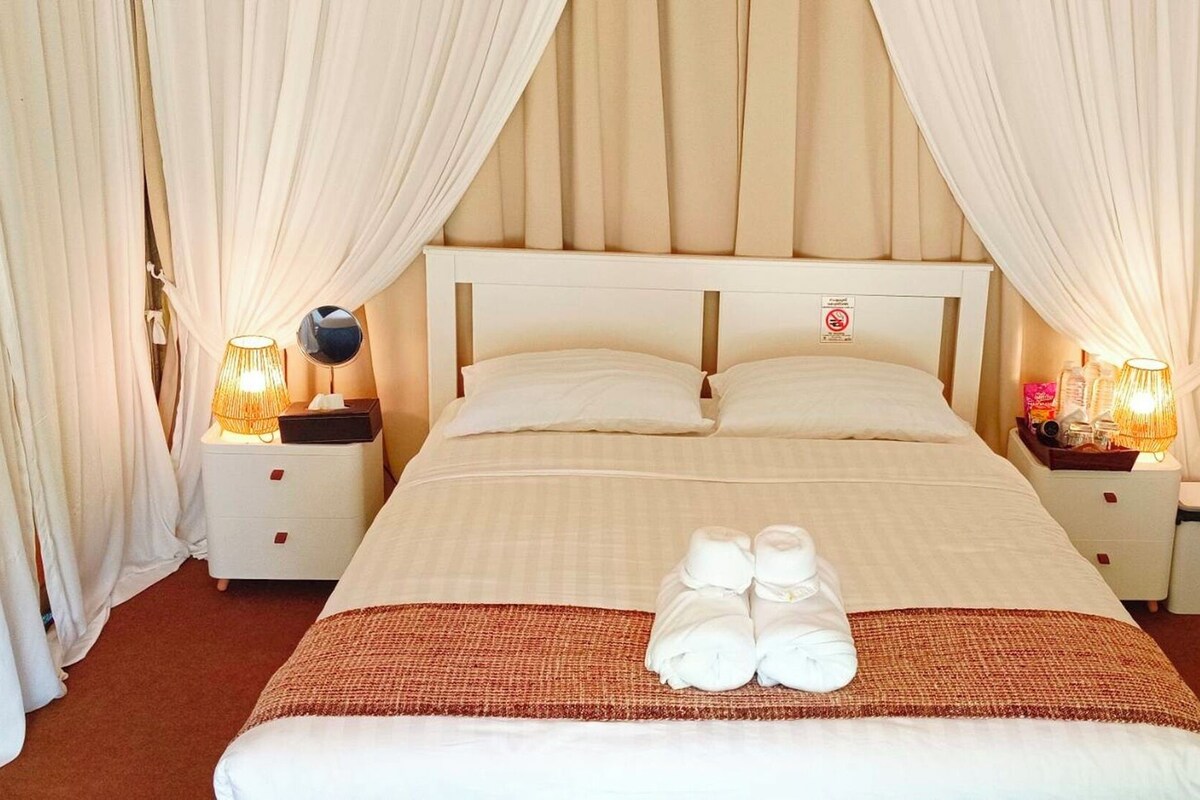 Una camera d'albergo con un letto, due comodini e un set di asciugamani.
