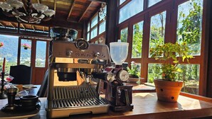 Una cafetera sobre una encimera de madera con vista al exterior.
