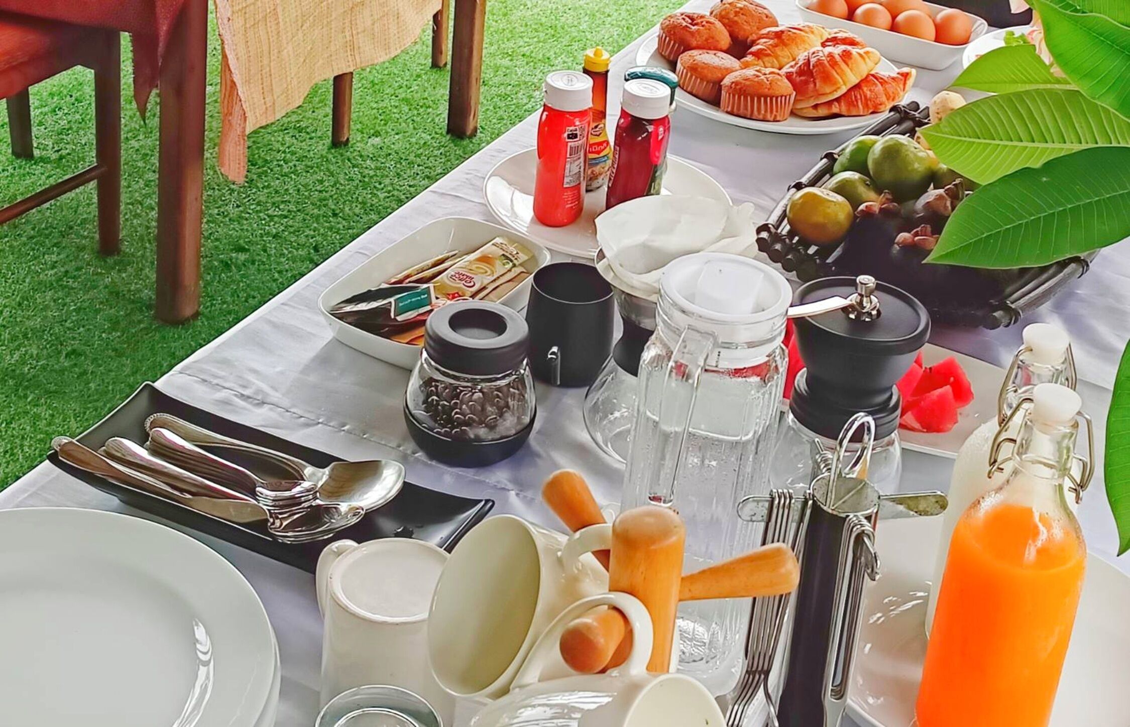 Ein Tisch im Freien mit verschiedenen Frühstücksartikeln, Besteck und Gewürzen.