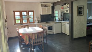 A kitchen with a dining table, chairs, a stove, and a sink.