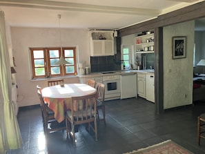 A kitchen with a dining table, chairs, a stove, and a sink.