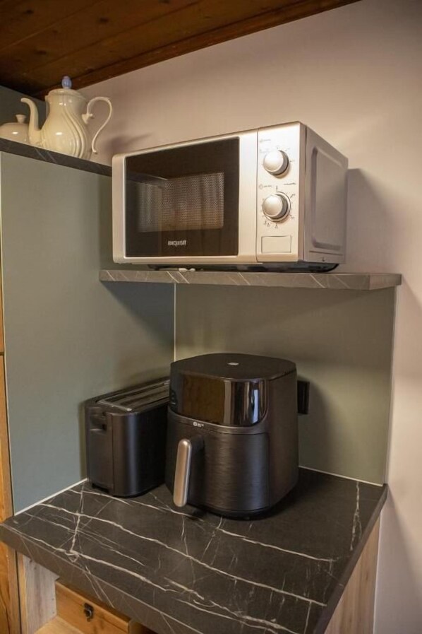 A kitchen with a microwave and a coffee maker on a marble countertop.