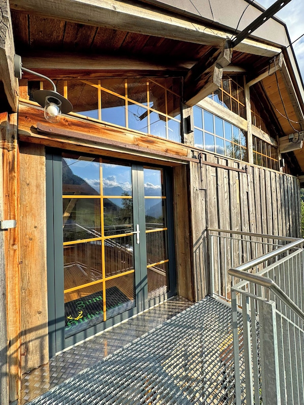 A wooden building with a metal staircase and a glass door leading to a balcony.