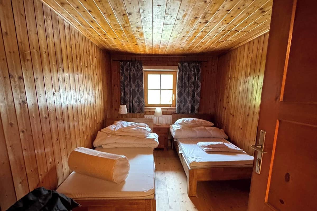 A cabin with two beds, a window, and a door.