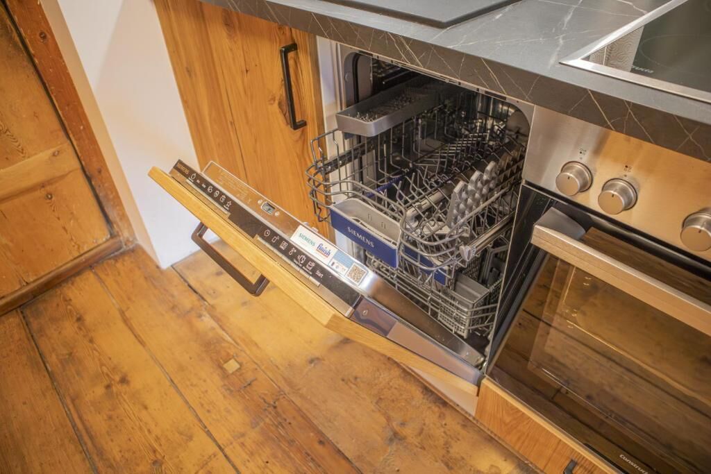 A kitchen with a dishwasher, oven, and wooden cabinets.