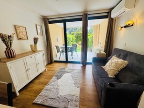 A living room with a sofa, a cabinet, a rug, and a view of an outdoor patio. - Superb renovated T2 - air conditioning - terrace - swimming pool - tennis court (Cannes)