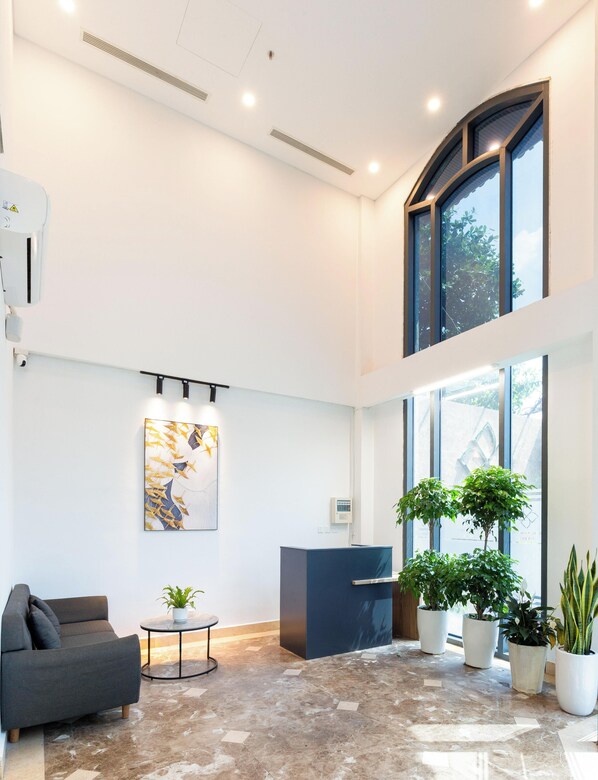 Eine großzügige Lobby mit einer Rezeption, einer Couch, einem Couchtisch und Topfpflanzen.