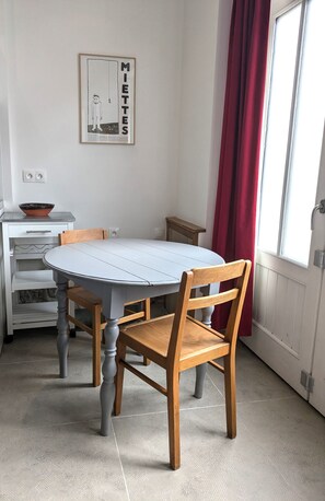 Ein Essbereich mit einem runden Tisch, Holzstühlen, einem weißen Schrank und einem roten Vorhang.
