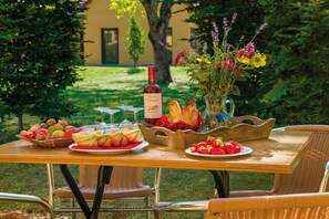 Une table dressée à l’extérieur, avec de la nourriture, du vin et des fleurs.