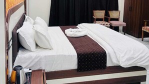 A bedroom with a bed, a ceiling fan, a wardrobe, and a seating area with chairs.