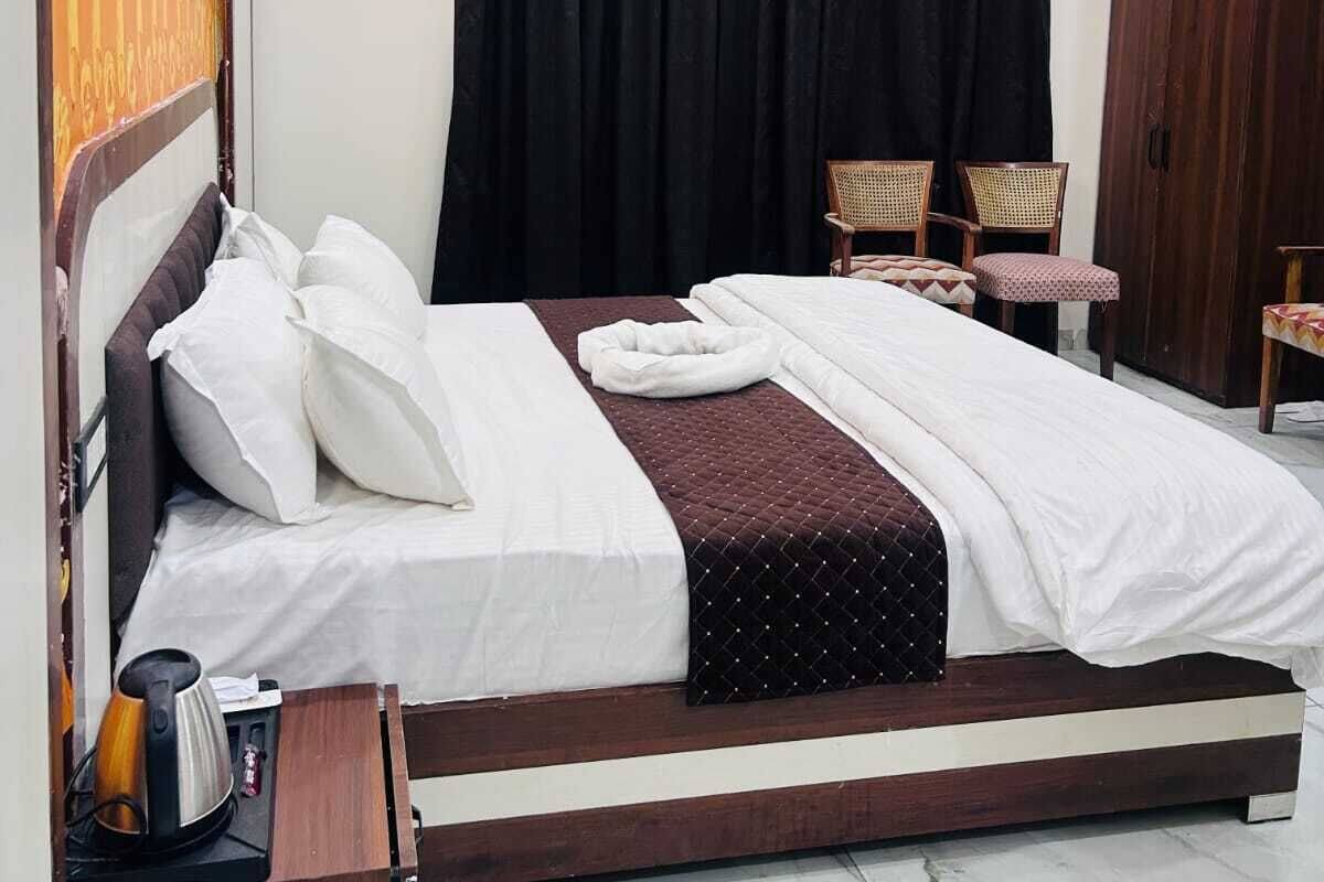 A bedroom with a bed, a ceiling fan, a wardrobe, and a seating area with chairs.