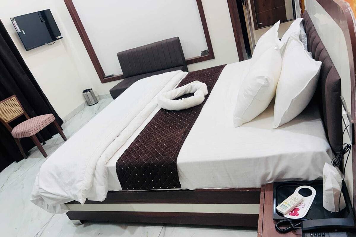 A neatly made bed with white linens, a brown quilted bedspread, and a headboard.