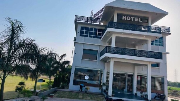 A multi-story hotel with a balcony, large windows, and a sign indicating it is a hotel.