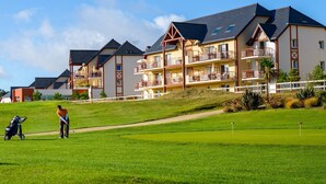 Ein Golfplatz mit einer Person, die bereit zum Putt ist, einer Golftasche und einem Kinderwagen.