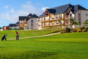 A golf course with a person preparing to putt, a golf bag, and a stroller. - Stylish coastal apartment with shared pool (Fréhel)